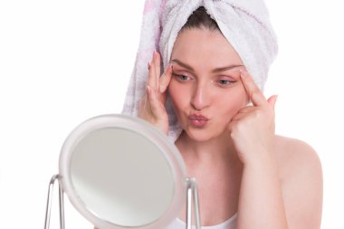 Kafasında havlu olan güzel bir kadın ve beyaz bir kameraya bakıyor.