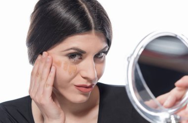 Genç bir kadın yüzüne makyaj yapıyor.