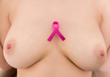 Göğüs kanseri farkındalığı. Beyaz arka planda pembe kurdele tutan genç bir kadın..