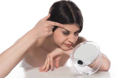 Genç bir kadın yüzüne makyaj yapıyor, beyaz arka planda izole edilmiş.