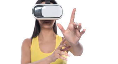 Kadın video kulaklık kullanıyor ve beyaz arka planda sanal gerçeklik gözlüklerine bakıyor.