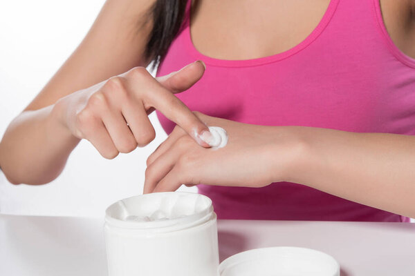 woman applying cream on her face, closeup