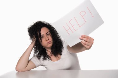 Elinde hüzünlü bir ifadeyle gazete tutan genç bir kadın.