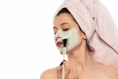 Kafasında havlu olan genç bir kadın ve beyaz kameraya bakıyor.