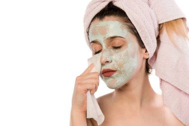 Yüzünde maske olan genç bir kadın kafasına makyaj kremi sürüyor.