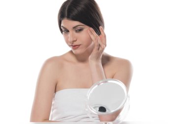 Güzel genç bir kadın yüzüne kozmetik krem sürüyor. Beyaz arka planda izole edilmiş.