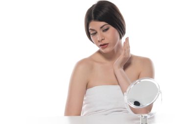 Güzel genç bir kadın yüzüne kozmetik krem sürüyor. Beyaz arka planda izole edilmiş.