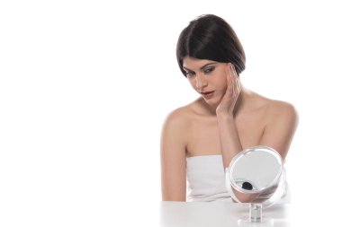 Güzel genç bir kadın yüzüne kozmetik krem sürüyor. Beyaz arka planda izole edilmiş.