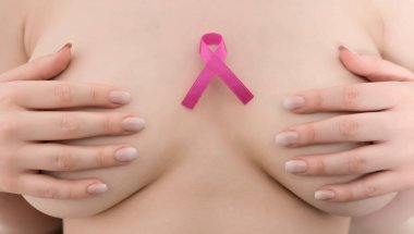 Göğüs kanseri farkındalığı. Elinde pembe kurdele tutan bir kadın..