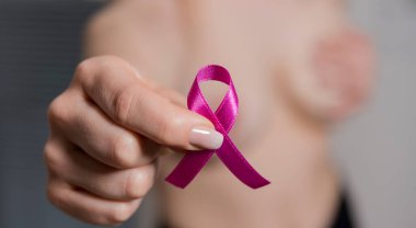 Beyaz arka planda pembe kurdele tutan kadın eli, göğüs kanseri farkındalığı konsepti