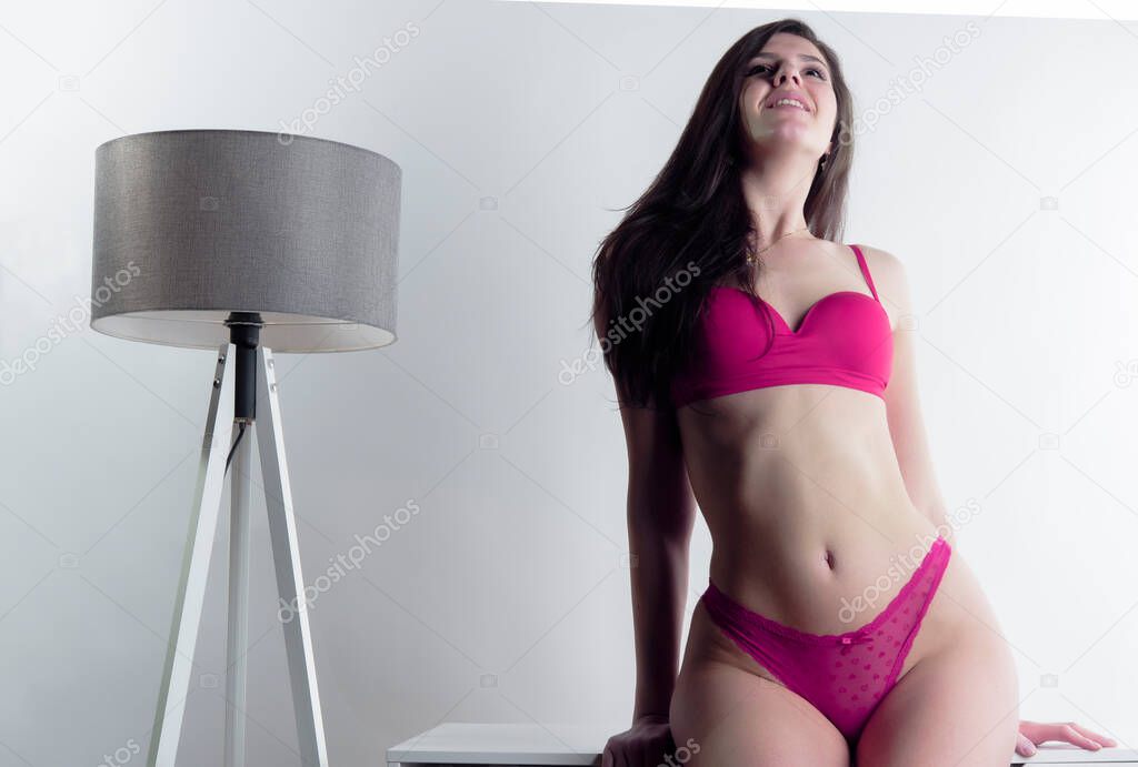 beautiful young woman in lingerie posing on a pink background