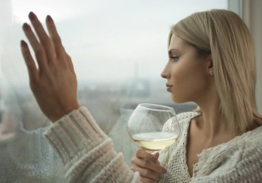 Pencerenin arkasında bir kadeh şarapla güzel bir kadın.