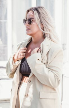 Beyaz önlüklü ve güneş gözlüklü güzel bir kadın şehirde poz veriyor.