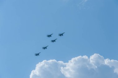 Askeri uçaklar beyaz bulutların üzerinde mavi gökyüzünde uçuyor.