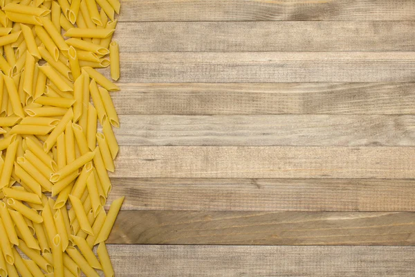 Strip raw pasta on wooden background — Stock Photo, Image