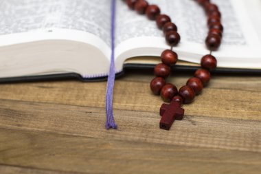 Açık İncil kitap ve koyu ahşap plakalar üzerinde tespih