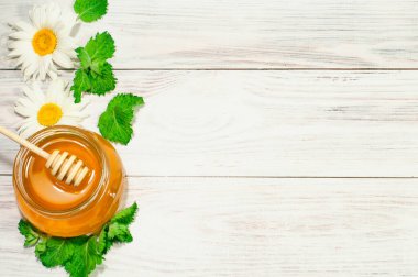 Tahta arka planda bir kavanozda taze bal, papatyalar, afişler, reklamlar
