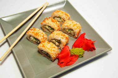 Asya yemeği suşisi gri bir tabakta yuvarlanıyor ve tahta sopalar.