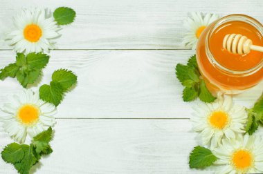 Tahta arka planda bir kavanozda taze bal, papatyalar, afişler, reklamlar