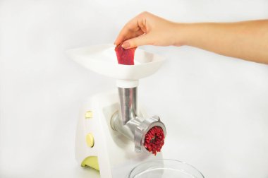 Adam elektronik et öğütücüsüne bir parça kırmızı et koyar.