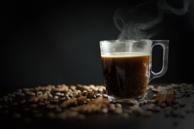 Siyah arka planda, tahıllı ve badyanlı bir fincan kahve.