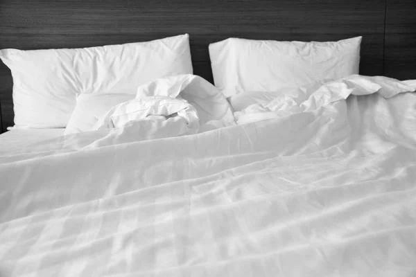 Calm and peaceful grainy image of all white bed room atmosphere. Pillows and blanket on empty bed, close up. Stay home concept.