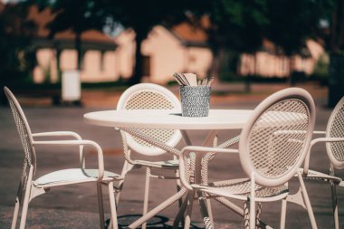 Beyaz masa ve sandalyeler sokakta.