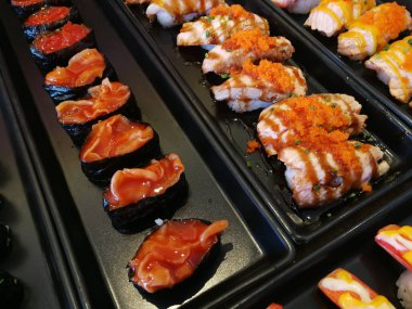 Siyah tabakta servis edilen çeşitli suşiler.