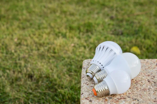 LED-Lampen - auf dem Beton mit grünem Grashintergrund — Stockfoto