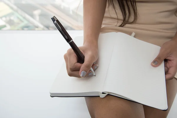 Frauenhand schreibt an Notizbuch — Stockfoto