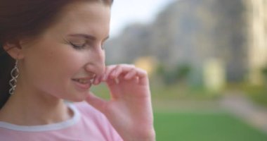 KADIN gülüyor ve dudaklarına dokunuyor.