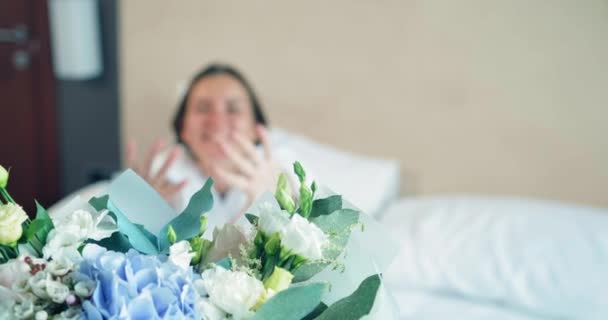 Visão turva da mulher sentada na cama chegando para buquê — Vídeo de Stock