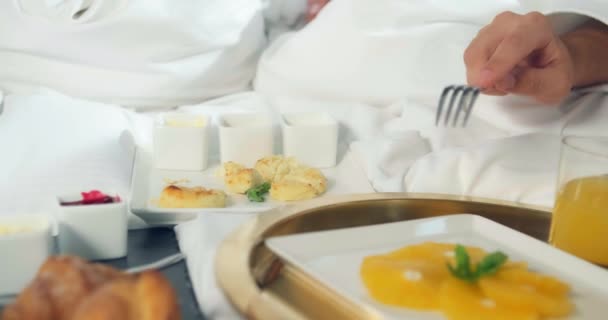 Pareja toma pedazos de buñuelo de queso crema en cama grande — Vídeos de Stock