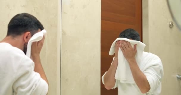 Hombre en albornoz toallitas cara con toalla esponjosa en el baño — Vídeos de Stock