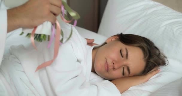 Man wakes up girlfriend and presents bouquet in hotel room — Stock Video