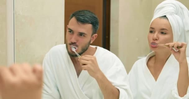 Adorável casal escova dentes de pé perto do espelho no banheiro — Vídeo de Stock