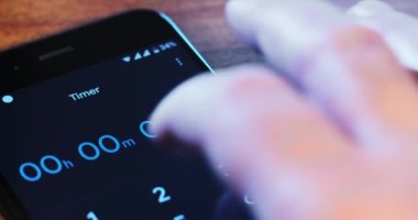 Adam ahşap masaya 20 dakikalık telefon uygulaması yüklüyor.