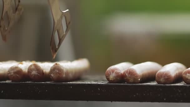 Cozinheiro vira salsichas grelhadas — Vídeo de Stock