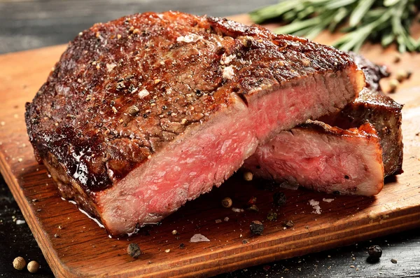 Mittelseltenes Ribeye-Steak auf Holzbrett, ausgewählter Schwerpunkt — Stockfoto