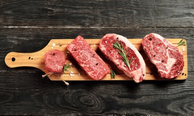 Fresh raw Prime Black Angus beef steaks on wooden board clipart