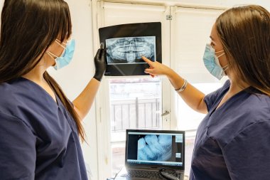 Diş muayenehanesinde insan çenesi üzerinde iki deneyimli diş hekimi röntgeni incelemesi