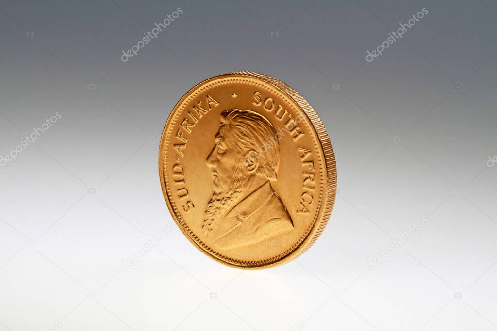Krugerrand gold coin stands on a gray background