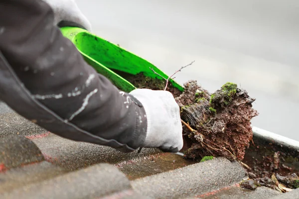 Bir kürekle ağır kirlenmiş bir oluğu temizlemek.