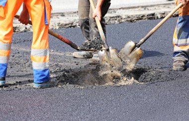 Kürekli işçiler yol yüzeyini yeniliyor