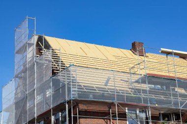Yeni çatı yalıtımlı tuğla bina iskelesi altında