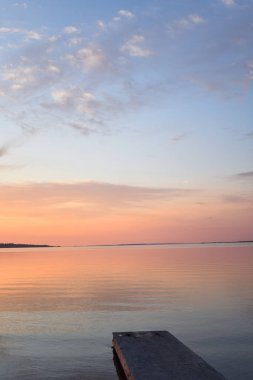 Gün batımının arkaplanındaki bulutlar nehir kıyısında