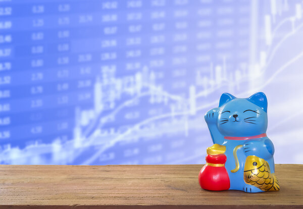 lucky cat bank on wooden table with blur stock market background