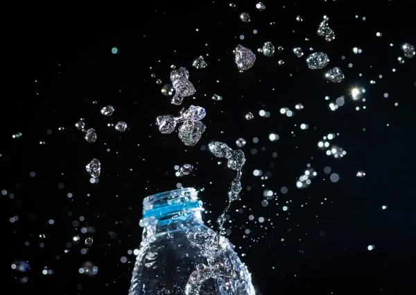 Water splashes from the bottle on black background