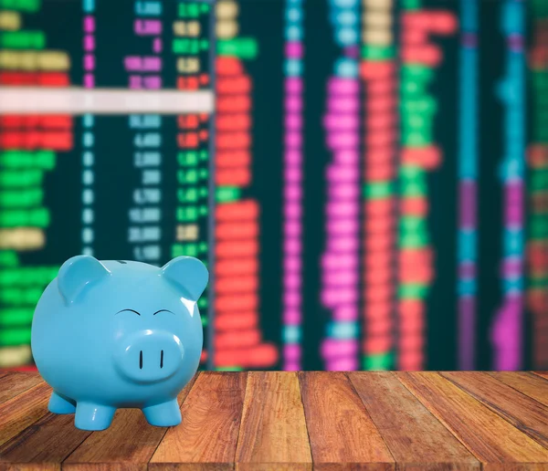 blue pig bank on wood background with blur stock market backgrou