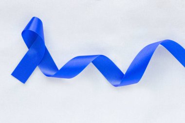 Fotokopi alanı olan beyaz kumaş üzerinde koyu mavi kurdele. Renkli Kanser Farkındalığı, Yaşlılar ve Diyabet Günü 'nde kolon kanseri, Çocuk İstismarı Önleme. Sağlık sigortası, sigorta kavramı.